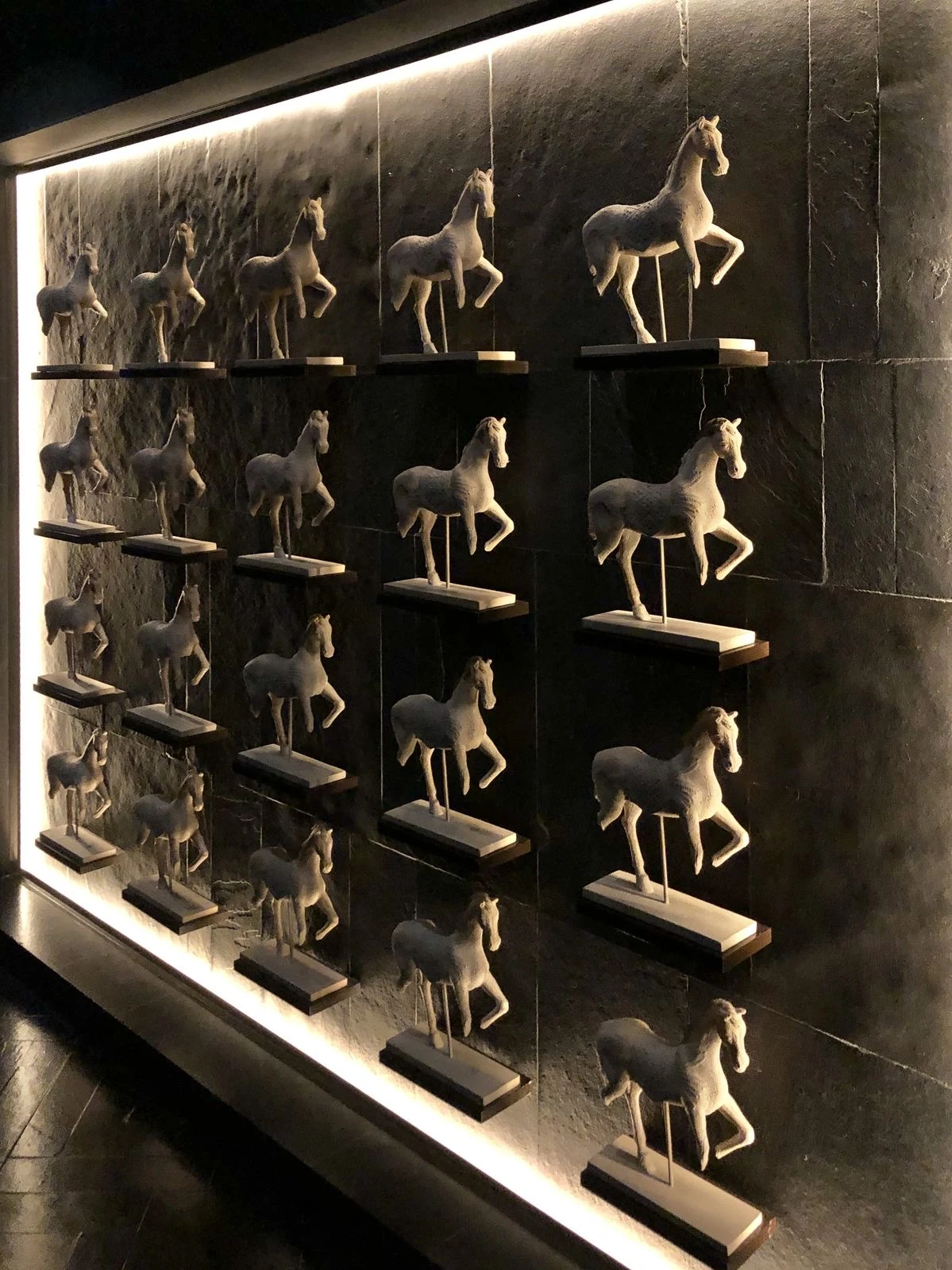 Collection de sculptures de chevaux sur un mur rétroéclairé
