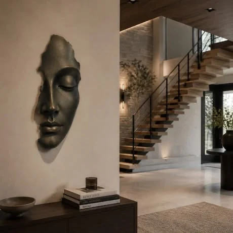 Masque sculpté mural en finition bronze près d’un escalier